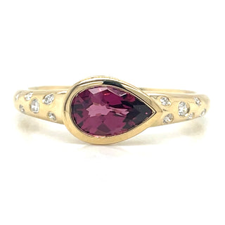 unique pear shaped garnet stone set into gold ring with diamonds set into the band