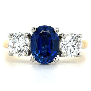 gold three stone gemstone ring with central sapphire and side diamonds