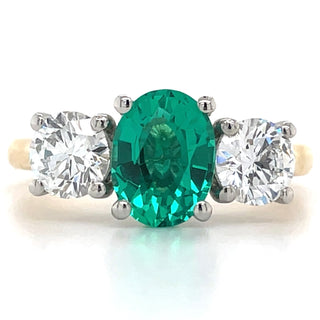 three stone gemstone ring with emerald centre stone and diamond side stones